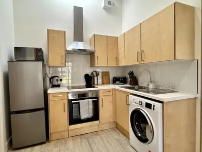 a kitchen with wooden cabinets and a washer and dryer at The Coorie in Bargrennan