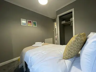 a bedroom with a bed with white sheets at Dunbeth House in Coatbridge