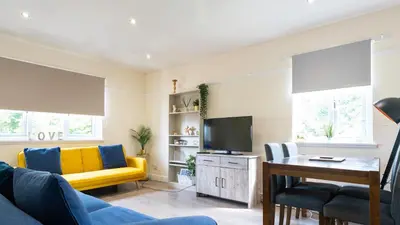 a living room with a yellow couch and a tv at The Riverside in Alloa
