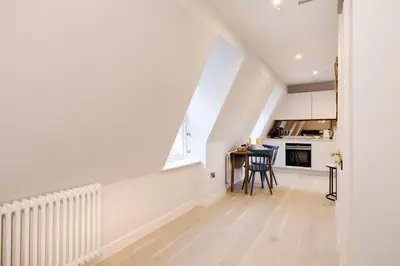 an attic kitchen with white cabinets and a table at JOIVY Tasteful Studios on Rose South in Edinburgh