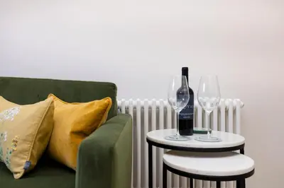a green couch with two wine glasses and a side table at JOIVY Tasteful Studios on Rose South in Edinburgh