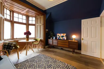 a living room with blue walls and a table and chairs at JOIVY Contemporary Cottage with Free Parking in Edinburgh