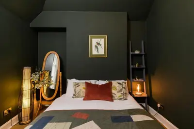 a bedroom with a bed and a mirror at JOIVY Contemporary Cottage with Free Parking in Edinburgh