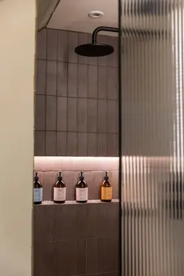 a row of bottles on a shelf in a bathroom at JOIVY Contemporary Cottage with Free Parking in Edinburgh