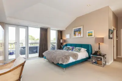 a bedroom with a blue bed and large windows at JOIVY Beautiful Penthouse with Terrace & Jacuzzi in Edinburgh
