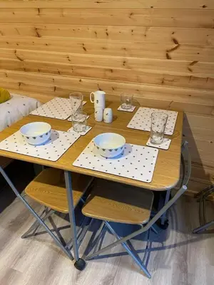 a wooden table with plates and glasses on it at Glamping Pods in Milngavie