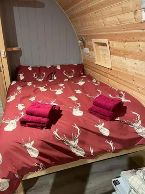 a bed with red sheets and red pillows on it at Glamping Pods in Milngavie