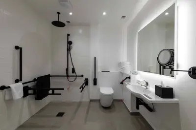 a white bathroom with a toilet and a sink at Sandman Signature Glasgow Hotel in Glasgow