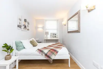 a white bedroom with a bed and a mirror at Luxury Modern 3 Bedroom Apartment in City Centre in Edinburgh
