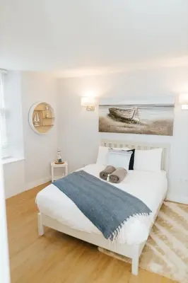 a white bedroom with a bed with a painting on the wall at Luxury Modern 3 Bedroom Apartment in City Centre in Edinburgh