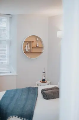 a white bedroom with a bed and a round mirror at Luxury Modern 3 Bedroom Apartment in City Centre in Edinburgh