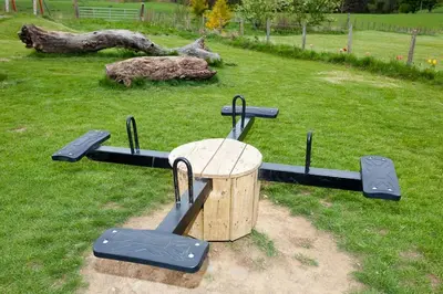 a trampoline park with a wooden table and trampoline at Laurel Cottage at Williamscraig Holiday Cottages in Linlithgow