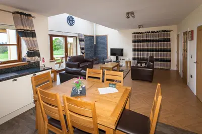 a dining room and living room with a table and chairs at 2 Eden at Williamscraig Holiday Cottages in Linlithgow