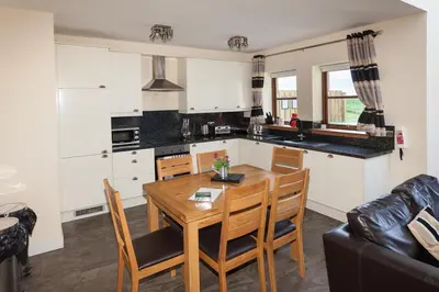 a kitchen and dining room with a wooden table and chairs at 2 Eden at Williamscraig Holiday Cottages in Linlithgow