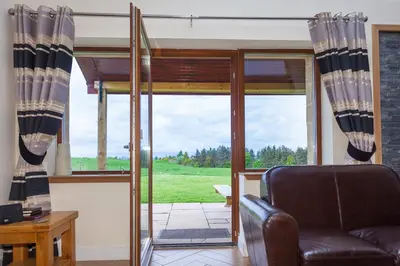 a living room with a chair and a window at 2 Eden at Williamscraig Holiday Cottages in Linlithgow