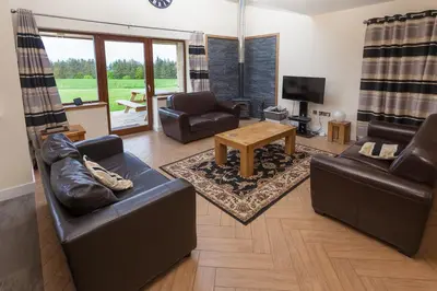 a living room with leather furniture and a television at 2 Eden at Williamscraig Holiday Cottages in Linlithgow