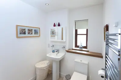 a white bathroom with a sink and a toilet at 2 Eden at Williamscraig Holiday Cottages in Linlithgow