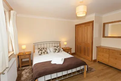a bedroom with a bed with two night stands and two lamps at Honeysuckle Cottage at Williamscraig Holiday Cottages in Linlithgow