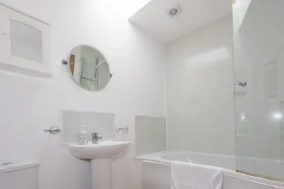 a white bathroom with a sink and a shower at Honeysuckle Cottage at Williamscraig Holiday Cottages in Linlithgow