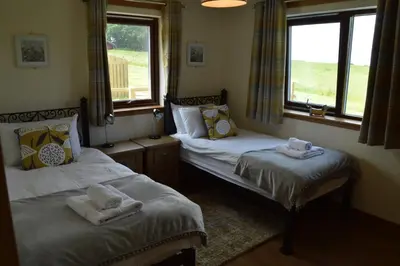 two beds in a room with two windows at The Farmhouse at Williamscraig Holiday Cottages in Linlithgow