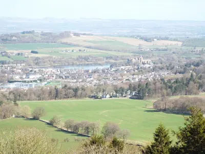 a view of a green field with a castle in the distance at The Farmhouse at Williamscraig Holiday Cottages in Linlithgow