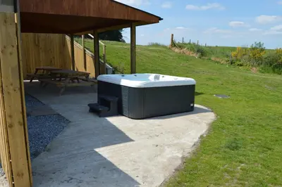 a hot tub sitting on a patio next to a picnic table at The Farmhouse at Williamscraig Holiday Cottages in Linlithgow