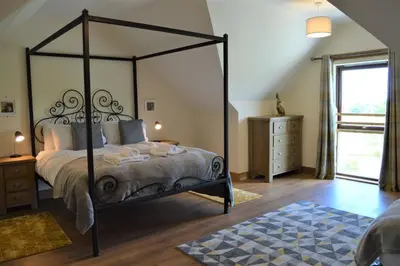 a bedroom with a canopy bed and a window at The Farmhouse at Williamscraig Holiday Cottages in Linlithgow
