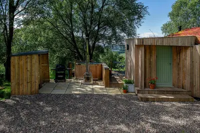 a wooden shed with a door and a patio at Craigmaddie Muir Roundhouse with Hot Tub Romantic, Luxury, Rural Stay for 2 Near Milngavie in Glasgow