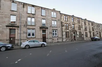 a white car parked in front of a brick building at The Warren Apartment in Greenock