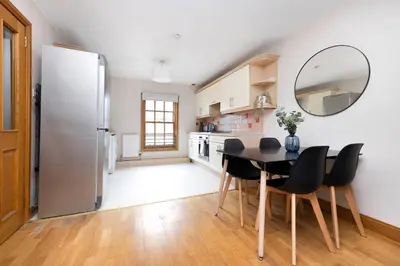 a kitchen with a table and chairs and a refrigerator at JOIVY Bright and Cosy Flat near The Scotland Gallery in Edinburgh