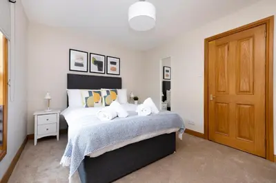a bedroom with a bed and a wooden door at JOIVY Bright and Cosy Flat near The Scotland Gallery in Edinburgh