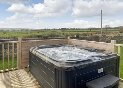a hot tub on a deck with a view of a field at Arran Hills in Kilwinning