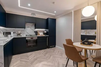 a kitchen with blue cabinets and a table and chairs at The Wilton Suite - Your Private 5* Escape! in Glasgow