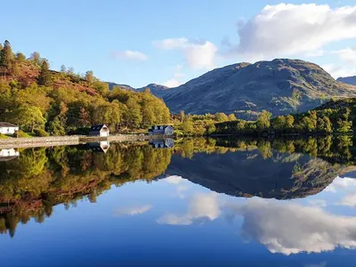 a reflection of a mountain in a body of water at Lochside Apartment in Stronachlachar