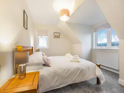 a bedroom with a large bed and a table at Fiadh Ruadh-Uk40008 in Gartmore