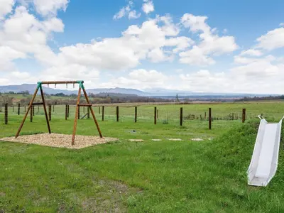 a swing set in a field with a fence at Fiadh Ruadh-Uk40008 in Gartmore