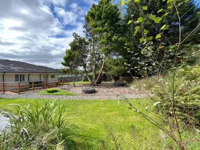 a yard with a house with a fence and trees at Holly - Apartment in Aberfoyle