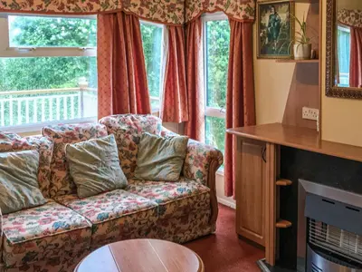 a living room with a couch in front of a window at Siskin Lodge - Uk39664 in Lunga