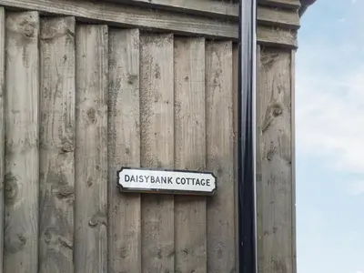 a sign on the side of a wooden wall at Daisybank Cottage in Crieff