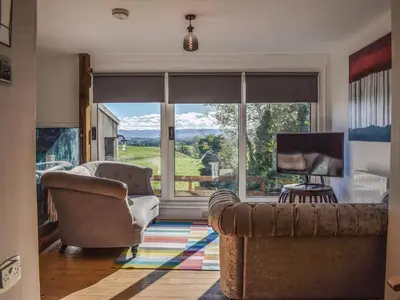 a living room with a couch and a large window at Daisybank Cottage in Crieff