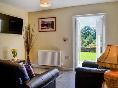 a living room with two couches and a sliding glass door at Hazel - Apartment in Aberfoyle