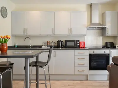 a kitchen with white cabinets and a table at Hazel - Apartment in Aberfoyle