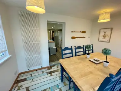 a dining room with a wooden table and blue chairs at Traditional Cottage in West Kilbride Village in Seamill