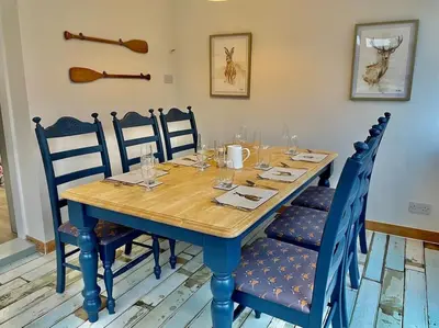 a table with blue chairs and a wooden table with glasses at Traditional Cottage in West Kilbride Village in Seamill