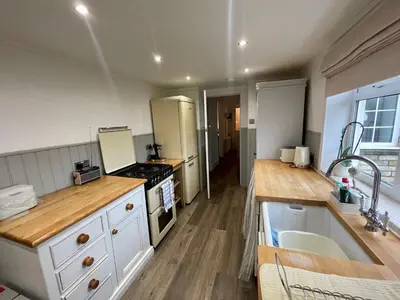 a kitchen with white cabinets and a stove top oven at Traditional Cottage in West Kilbride Village in Seamill