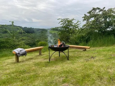 a fire pit and a bench in a field at Ecosse Glamping in Crossford
