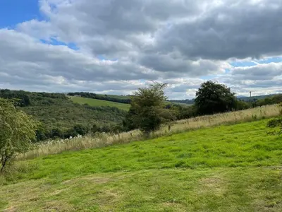 a grassy hill with a fence in a field at Ecosse Glamping in Crossford