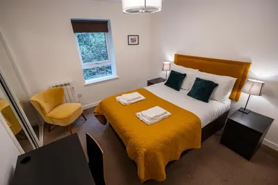 a small bedroom with a bed and a chair at Balvenie Apartment in Oban