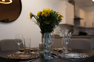 a table with glasses and a vase of flowers on it at Balvenie Apartment in Oban
