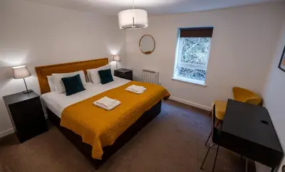 a bedroom with a large bed with a yellow blanket at Balvenie Apartment in Oban